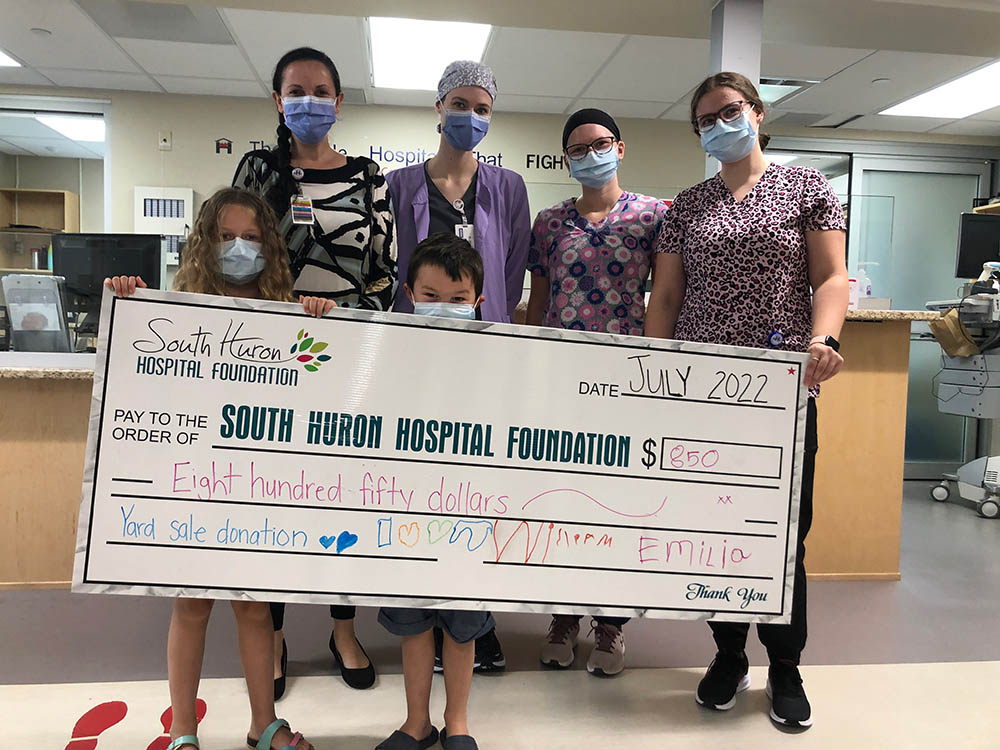 Group of children and adults holding large display cheque